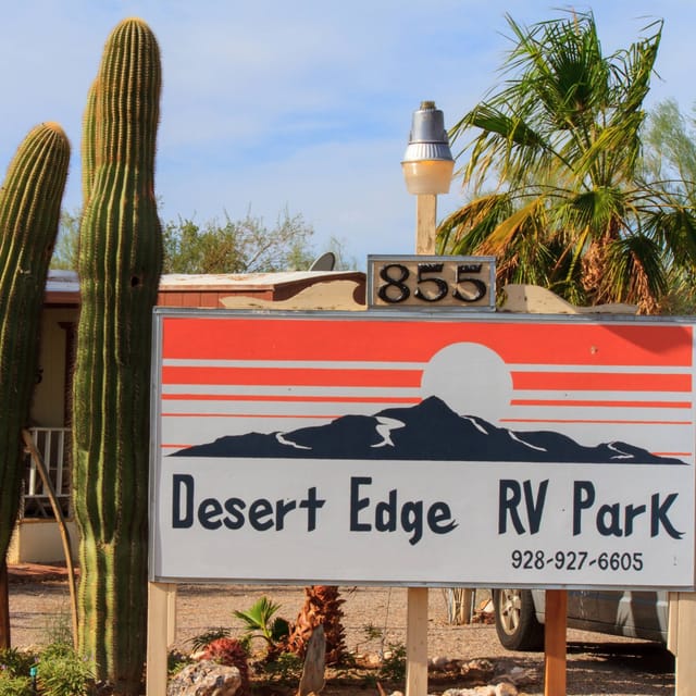 Desert Edge RV Park's entrance sign at 855 E. Rogers Place, framed by saguaros