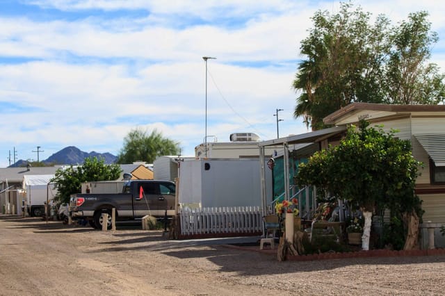A park lane lined with park models and RVs, with mountains in the distance